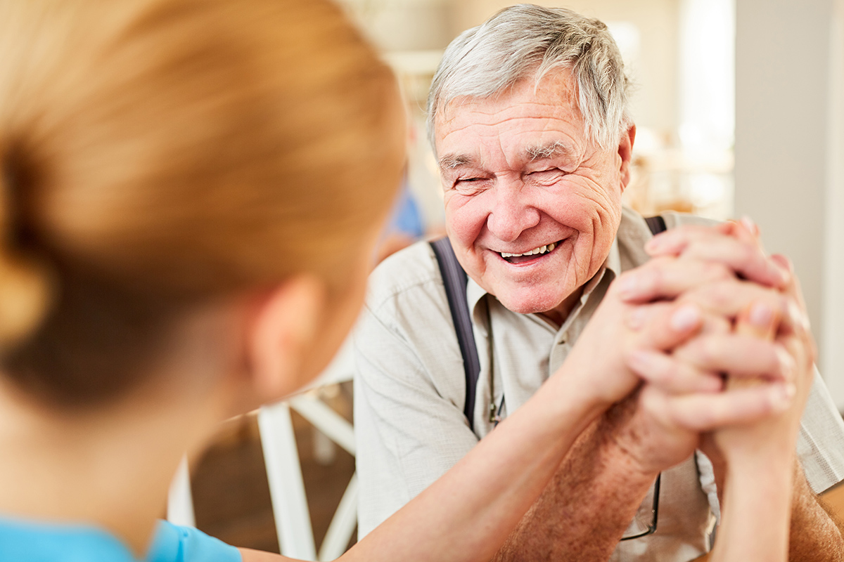 Foto: Pflegerin mit älterem lachenden Mann